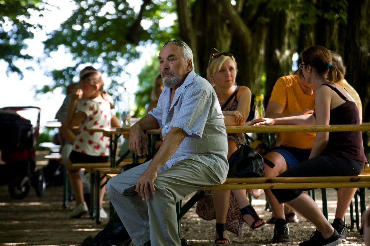 piknik rodzinny w Mogilanach 2019 - starsze osoby w alejce grabowej na ławkach