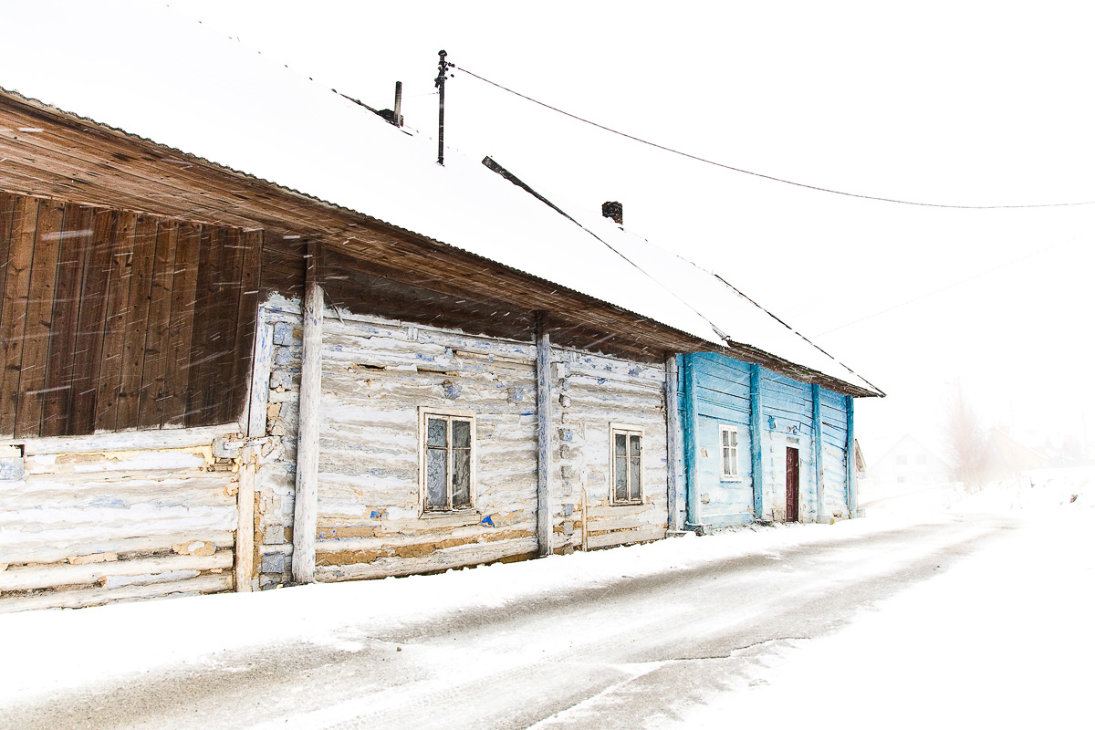 zadymka zimą w Mogilanach na tle starego drewnianego domu